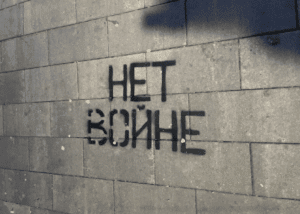 "No War" stencilled in black graffiti in Russian against a cinder block wall