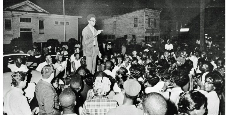 H. “Rap” Brown stands atop a car in the African American section of Cambridge, Md., July 24, 1967 delivering a fiery black nationalist speech denouncing white dominated society and urging African Americans to fight back. Later that night, Brown was wounded by shotgun pellets before he left town. In the early morning hours, someone set fire to an African American school that ended up burning two square blocks while the town’s firemen stood by. Maryland Gov. Spiro T Agnew immediately denounced Brown and he was soon charged with inciting to riot, along with other crimes. The National Guard was again called out to occupy the town. Brown faced other legal woes, but charges in the Maryland case were ultimately dropped several years later. The incident marked the end of the mass civil rights movement in Cambridge that began in 1962. Photo Credit; Washington Area Spark (https://www.flickr.com/photos/washington_area_spark/49222107273/in/album-72157702777400382/)