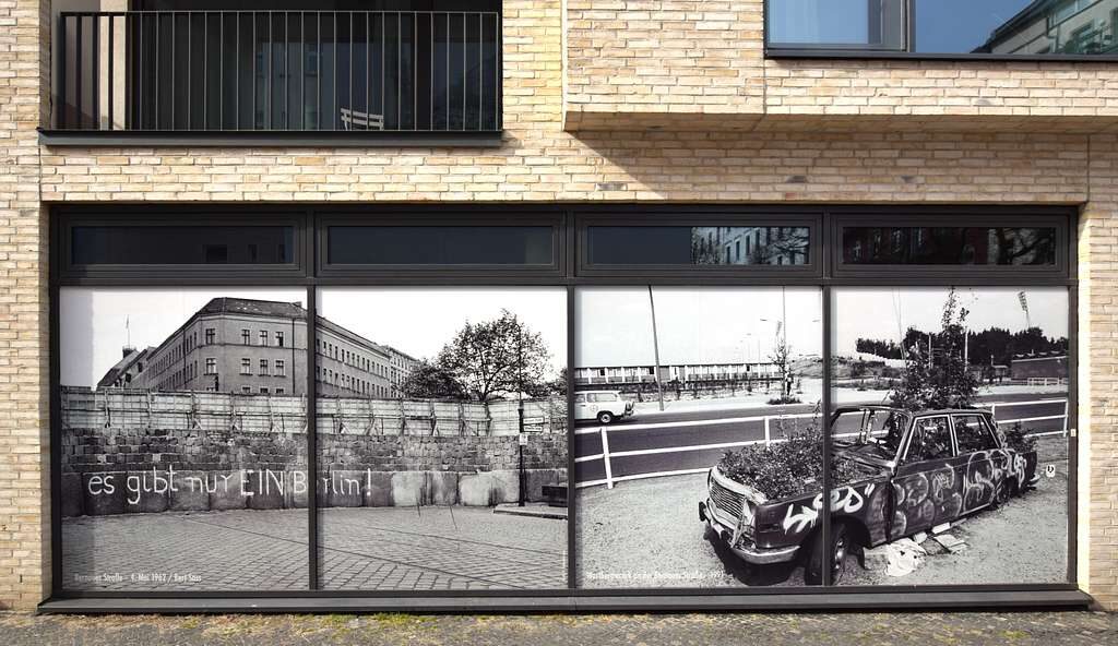 Berlin Wall vs Fall of the Wall poster on a wall at the Schwedter Straße in Berlin, Germany (2022). Via wikimedia commons