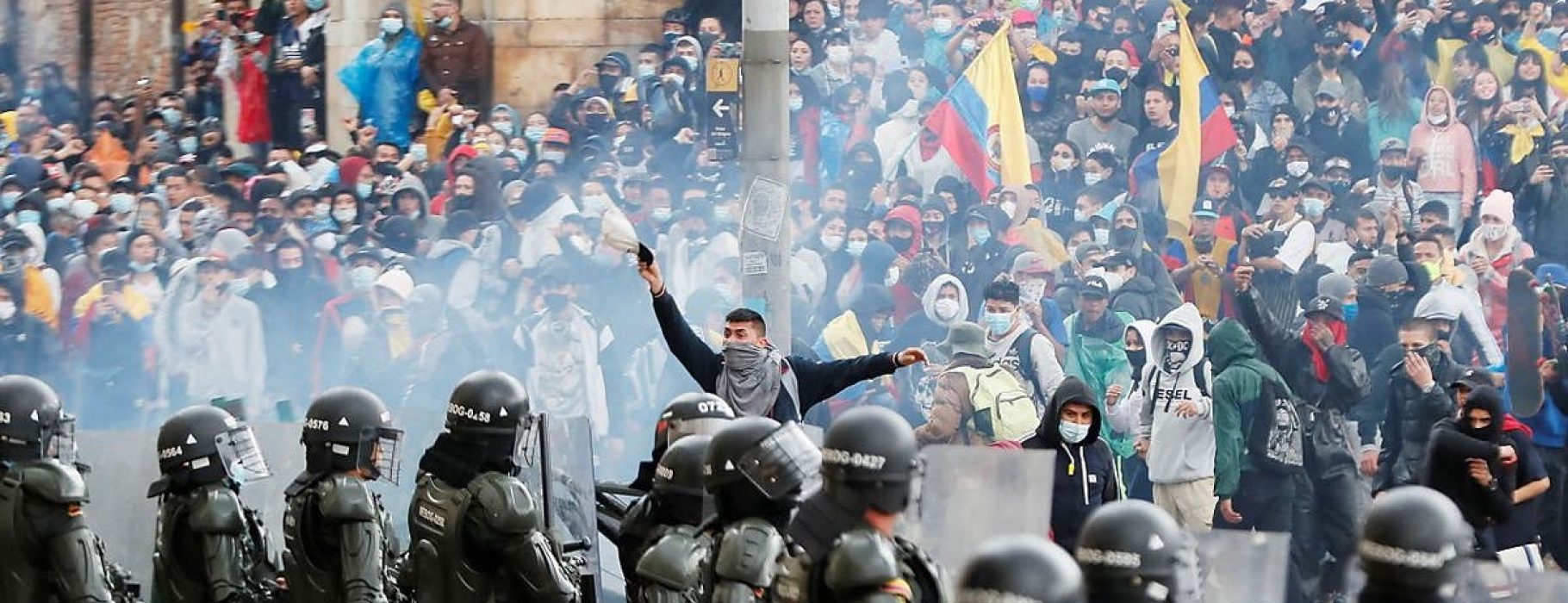 Colombian protesters advance through tear gas towards a police lline