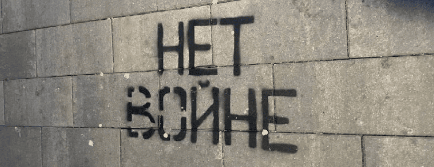 "No War" stencilled in black graffiti in Russian against a cinder block wall