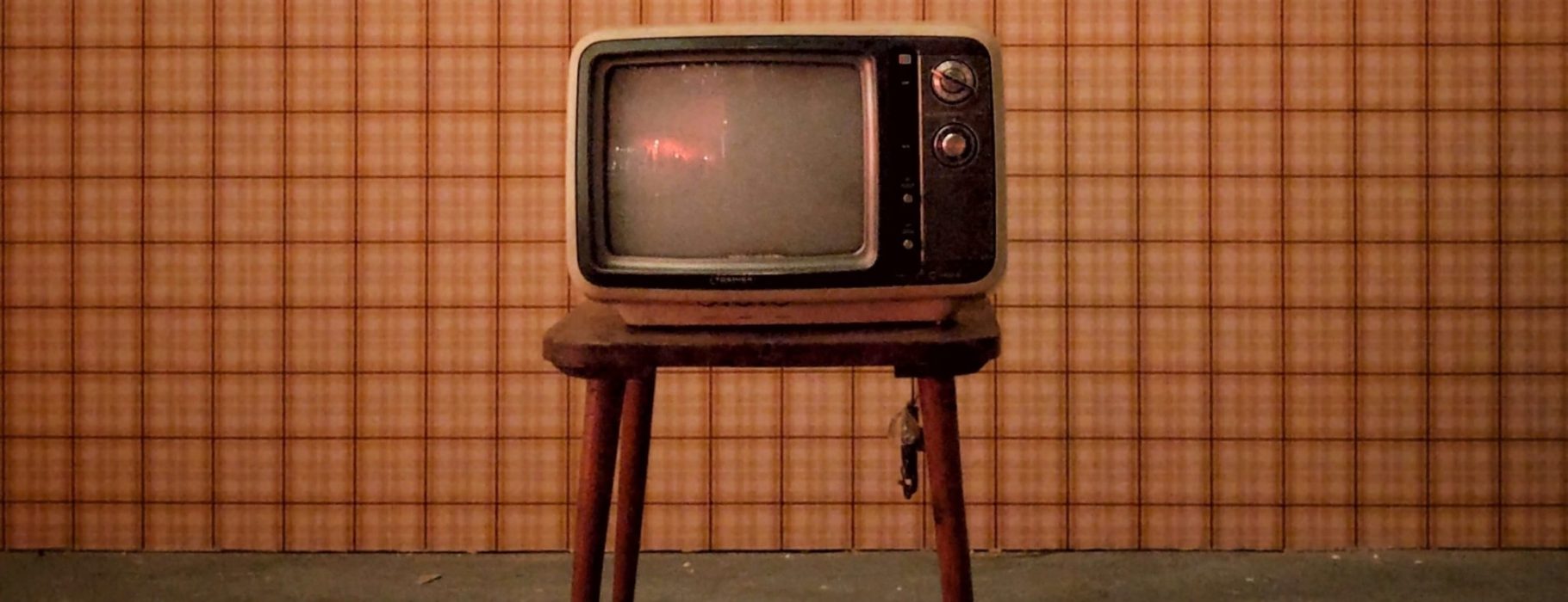Vintage television set against a checked wallpaper background